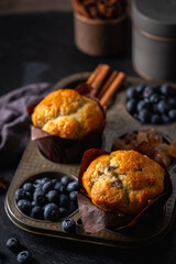 Sweet homemade pastries muffin with blueberries and fresh berries on dark background.