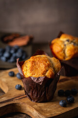 Sweet homemade pastries muffin with blueberries and fresh berries on wooden background.