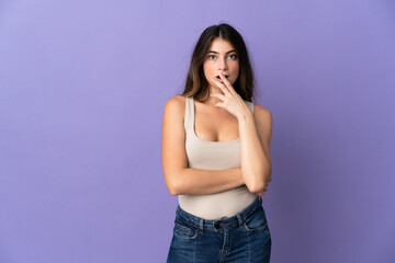 Young caucasian woman isolated on purple background surprised and shocked while looking right