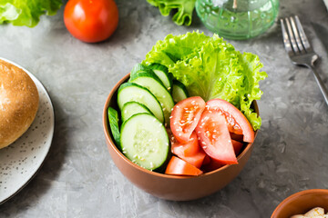 Fresh vegetable bowl with cucumber, tomato and lettuce on the table at home. Close-up