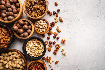 Assortment of nuts in bowls on white background top view with copy space. Healthy snack food.