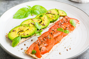 Appetizing bruschetta with avocado and tomatoes on grain bread on a plate on the table. Close-up