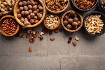 Assortment of nuts in bowls on stone background top view with copy space. Healthy snack food.