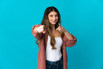 Young caucasian woman isolated on blue background pointing front with happy expression