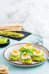 Bruschetta on crispy bread with avocado and boiled egg on a plate. Vertical view