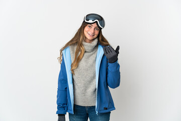 Skier girl with snowboarding glasses isolated on white background inviting to come with hand. Happy that you came