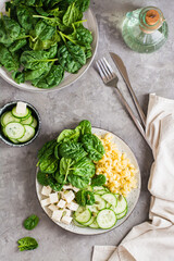 Bowl with pasta, cucumber, cheese and spinach on the table.  Top and vertical view