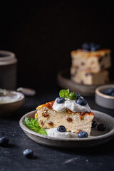 Baked homemade cottage cheese casserole or pudding with raisins serving with blueberry and sour...