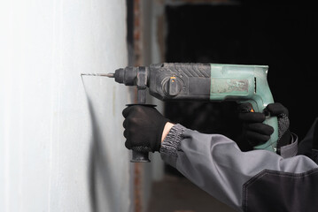 Worker is drilling the wall by the perforator close up.