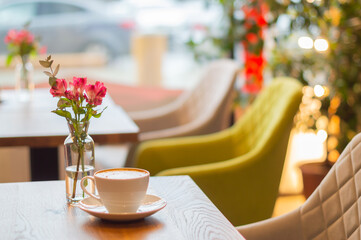 cappuccino coffee and flowers on the table in the cafe. a table in a cafe