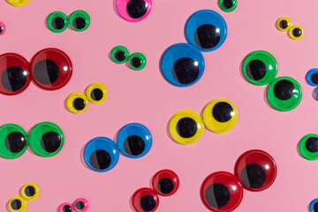 Multicolored plastic eyes on a pink background. Googly eyes.