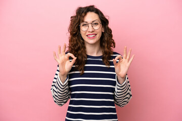 Young caucasian woman isolated on pink background showing ok sign with two hands