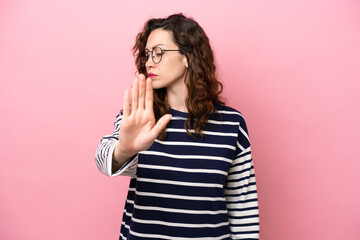 Young caucasian woman isolated on pink background making stop gesture and disappointed