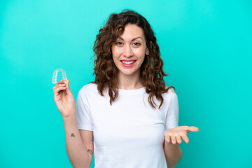 Fototapeta premium Young caucasian woman holding a envisaging isolated on blue background with shocked facial expression