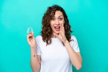 Young caucasian woman holding a envisaging isolated on blue background shouting with mouth wide open