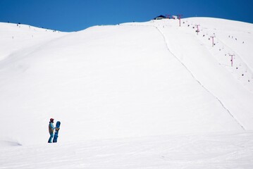 Joven con tabla de snowboard en una montaña nevada