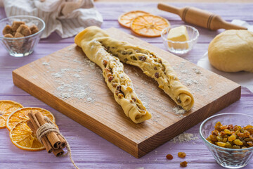 Step-by-step cooking of kraffin ( cruffin),  yeast Easter cake with raisins. Step four, roll the dough with raisins into a roll and cut into two parts