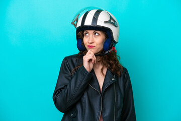 Young caucasian woman with a motorcycle helmet isolated on blue background and looking up