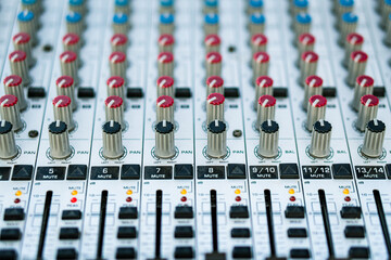 Close-up of the handles and sliders of an audio mixer. Blurred back.