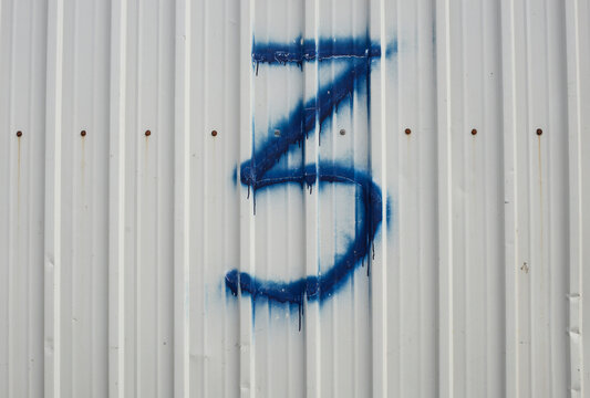 number 3 in blue on a background of corrugated sheet metal. industrial style.