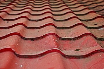 Old dirty tiles on the roof of the building. The texture of the red background.