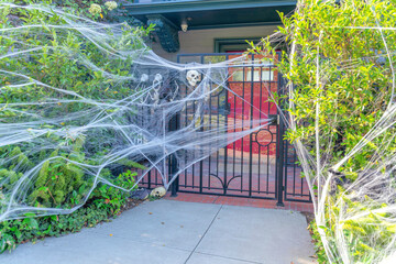 House entrance with fake webs and skeletons at the front of the iron gate in San Francisco, CA
