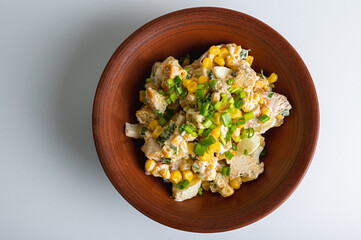 Salad with grilled chicken fillet, breadcrumbs, quail eggs, corn on a clay plate isolated on a white background. Selective focus. The concept of delicious spring salads