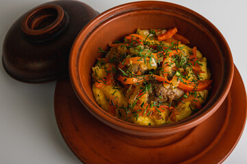 Chicken rice from a clay pot, porridge, rice in a clay brown pot with vegetables on a light background