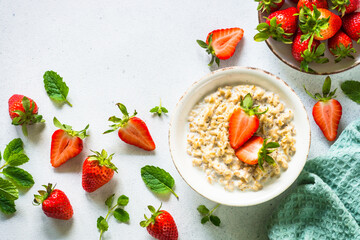 Oatmeal porridge with organic strawberry on white background. Top view.