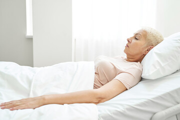 Female pensioner resting in bed ward of medical center