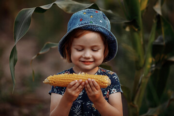 Happy little girl holding an ear of corn.