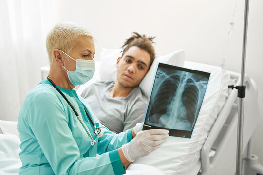 Aging female doctor explaining x-ray to man