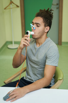 Man breathing into tube of spirometer during test
