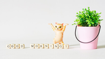 Funny dancing toy cat next to a bucket with a and the inscription good morning. Good morning wish...