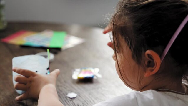 Caucasian preschool girl doing crafts with plastic bottle and paints. Recycle upcycling waste. Sustainable lifestyle