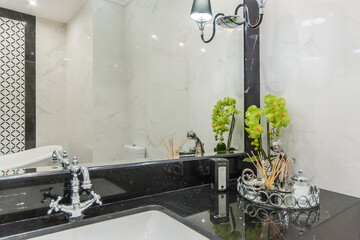The bathroom has a black marble countertop sink, stylish accessories and a large mirror.