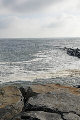 Calm ocean inlet with boulder jetty as dark storm clouds approach