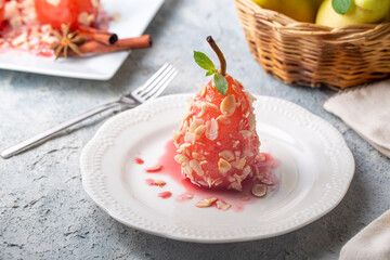 A poached pear dessert sprinkled with almond pieces. A taste of Turkish desserts, pear dessert. Poached pears in red wine.