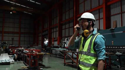 One man specialists inspect commercial, Wear safety uniform work with a radio at metal industry factory. Handsome caucasian worker in protective working clothes and with white helmet on head leaning.