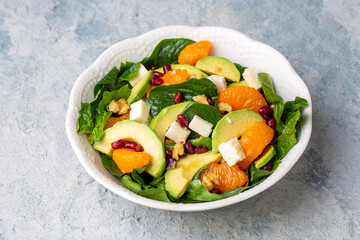 Close up view of spinach, avocado salad with orange, pomegranate and walnut