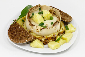 Baked goat cheese on pineapple with bread and wild garlic