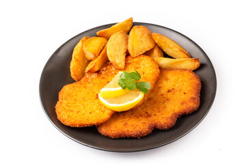 Chicken schnitzel with sauce, fried potatoes and lemon in a plate