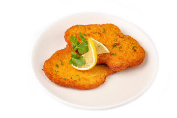 Chicken schnitzel with sauce, fried potatoes and lemon in a plate