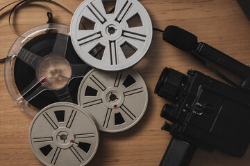 Old 8 mm video camera with film reels on wooden background. Copy space. Selective focus.