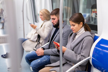 Obraz premium People browsing in smartphone in subway