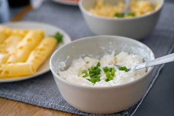 homemade breakfast, yellow cheese with holes, small sliced tomatoes, cottage cheese, egg paste, eggs, chives, tea, orange, carrot and grapefruit juice in wine glasses, black tableware.