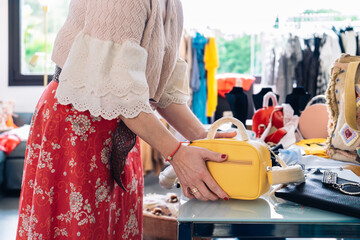 cutout shot of a woman picking up a handbag to buy it in a fashion shop. shopping concept.