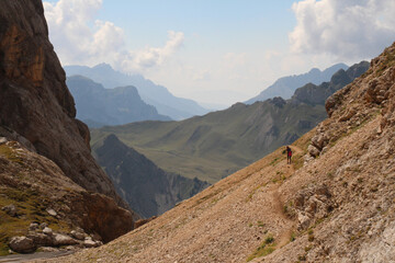 Fototapeta premium Mountain landscape with a tourist on a hiking trail at Passo Ombretta in a sunny day, Italian Alps.