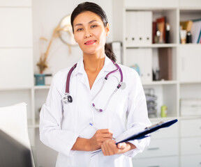 Positive woman asian doctor is standing with documents in clinic