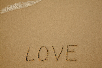 Love - handwritten on the soft beach sand.